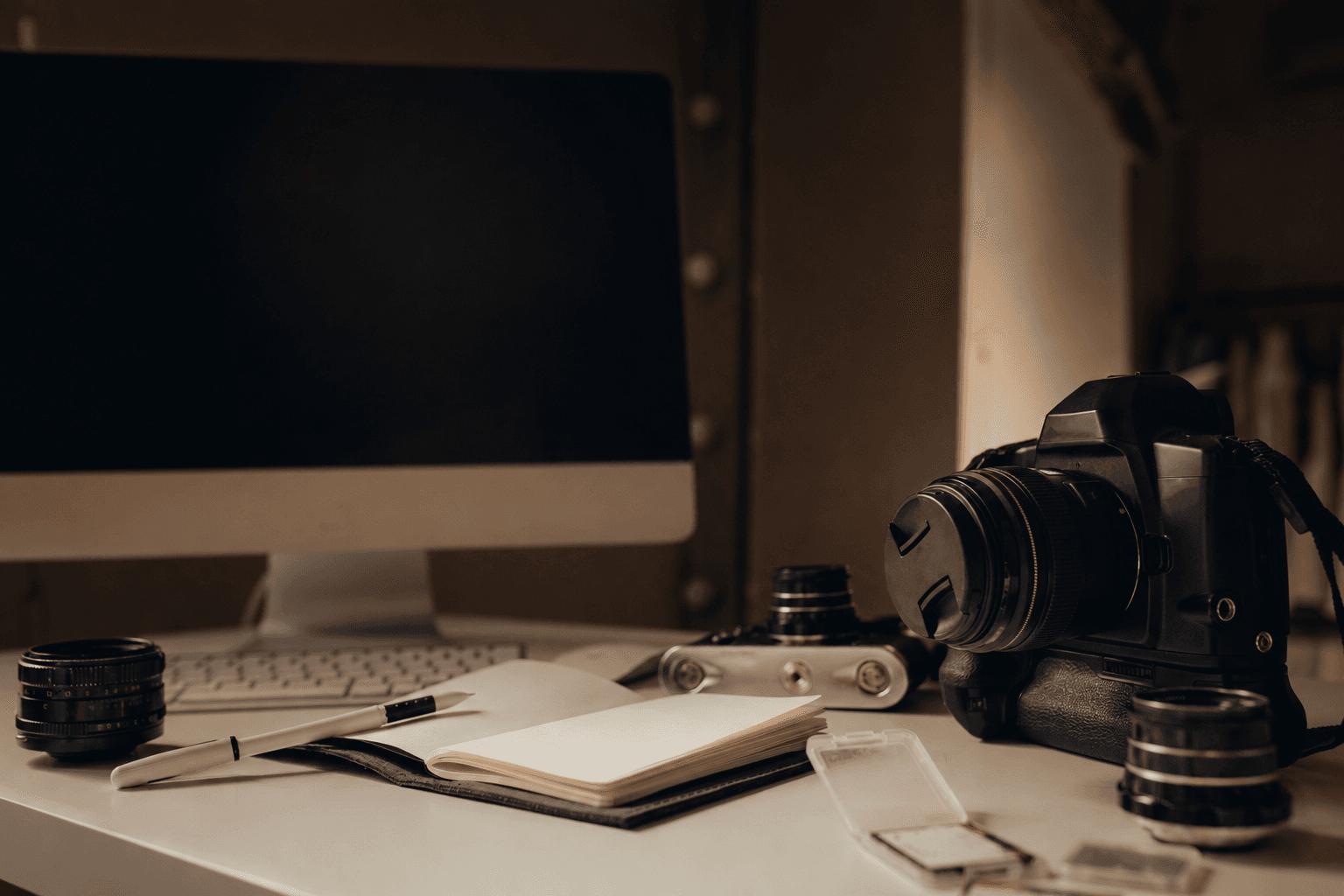 Photographer workspace with cameras, lenses, and editing monitor